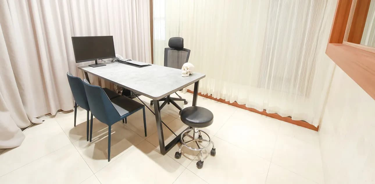 Consultation room with a desk, monitor and chairs for the patient