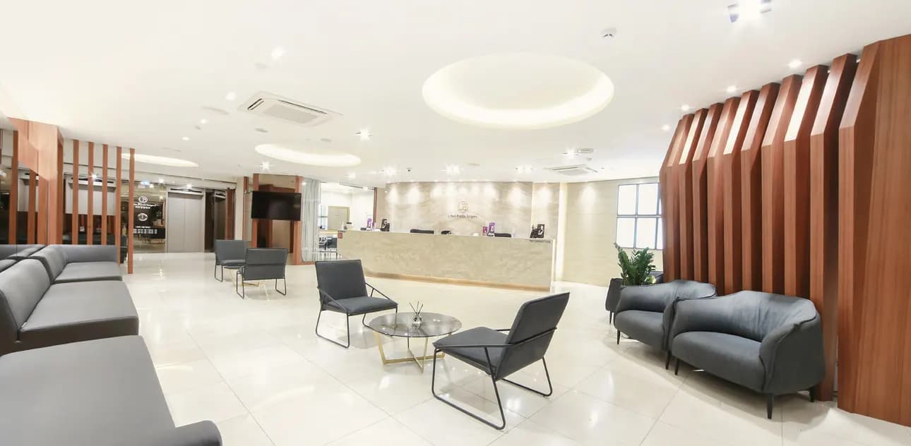 Bright clinic lounge with grey sofas, wooden wall panels and a marble reception desk