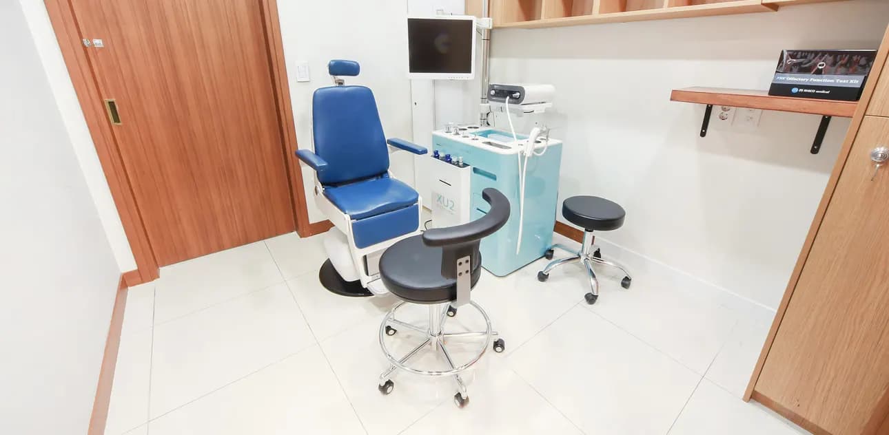 Treatment room with a reclining blue chair and a wall monitor