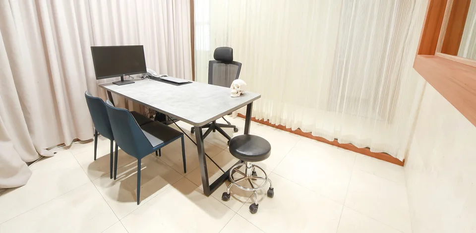 A consultation room at Urban Plastic Surgery, our partner clinic in Seoul, where a small skull model sits on the grey desk beside a computer monitor.